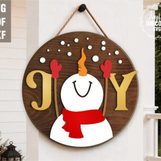 Christmas snowman JOY door hanger SVG featuring a smiling snowman with a red scarf, mittens, and falling snowflakes on a round wooden sign, laser cut file for Glowforge, CNC machines, and other lasers.